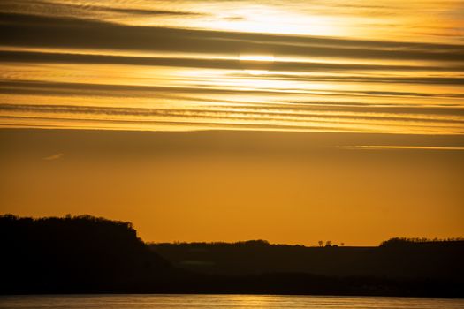 Breathtaking view of a golden sunset over the Mississippi River with silhouetted hills, Pepin, Wisconsin.
