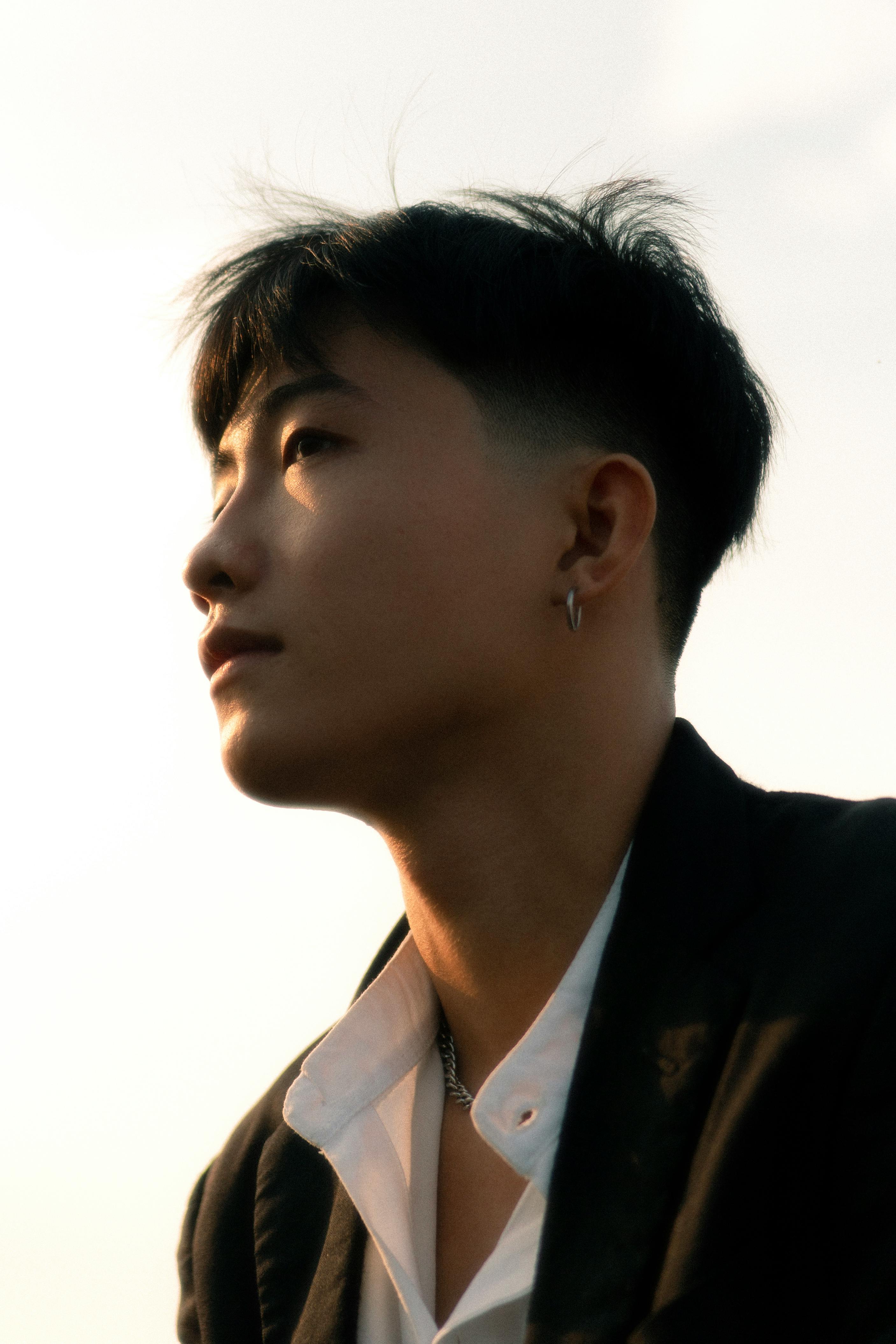 Portrait of a young adult in thoughtful pose against a sunset sky.