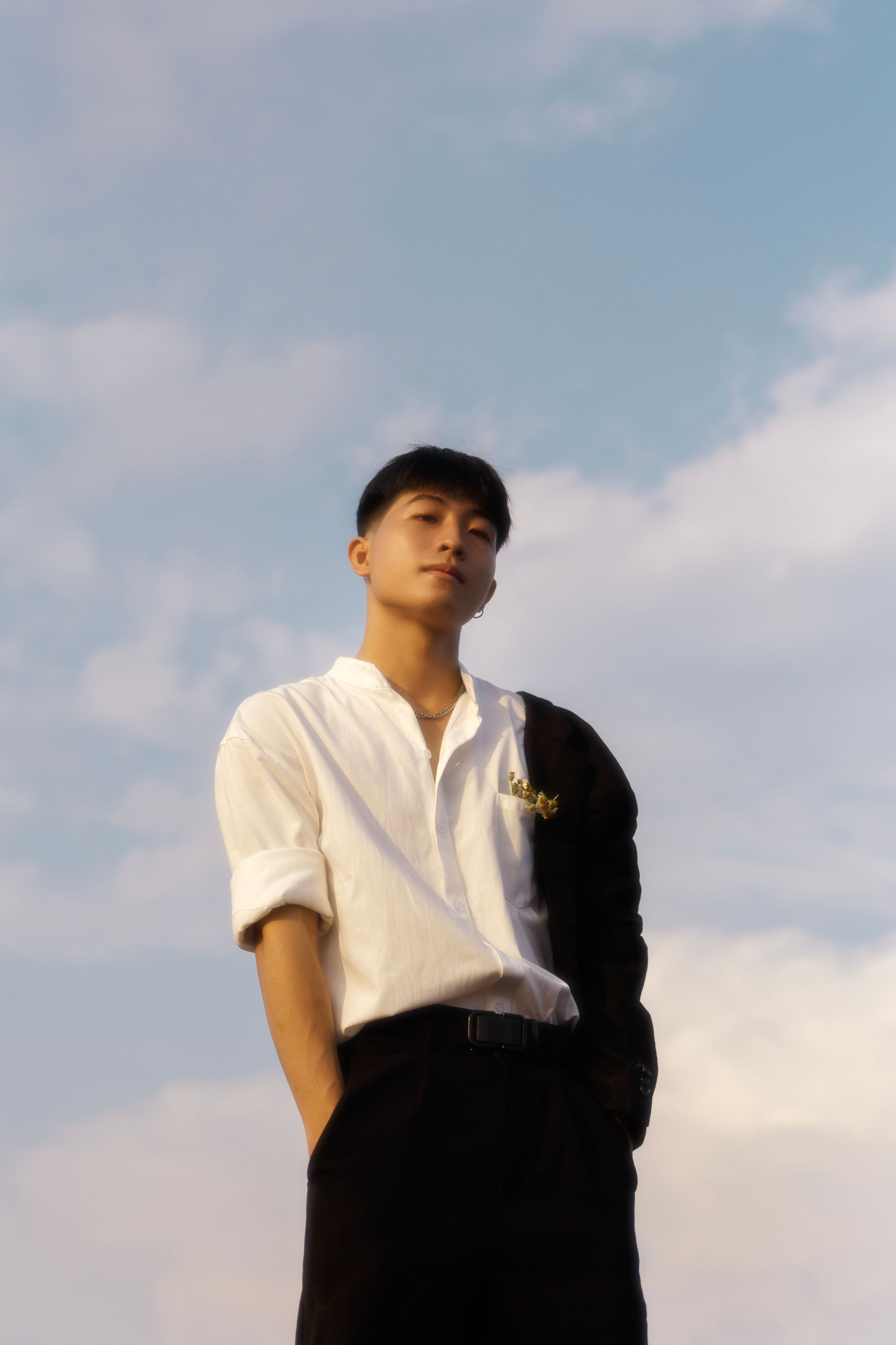 Portrait of a young man with clear sky background, showing modern fashion sense.