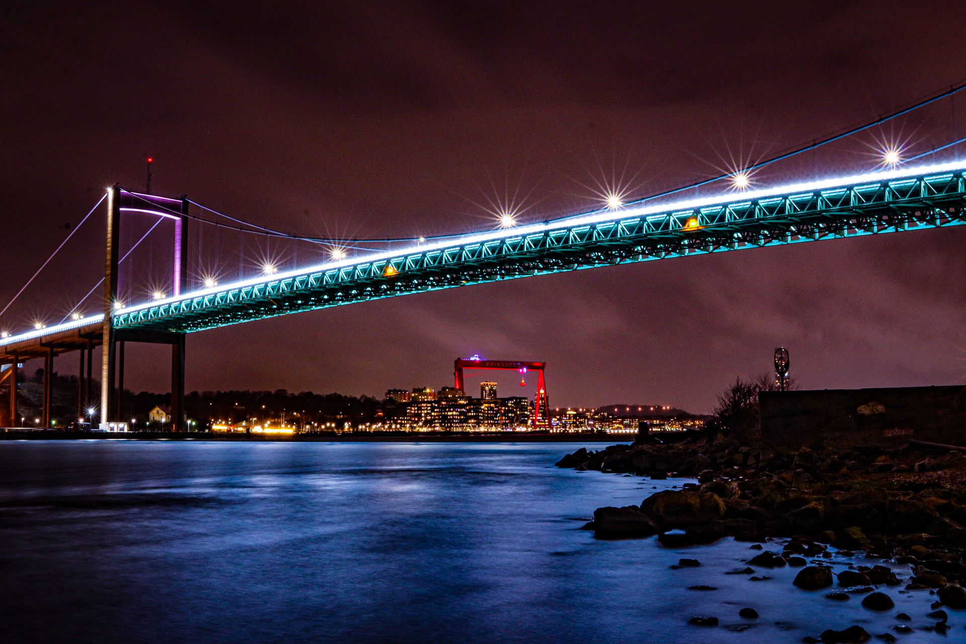 Vibrant long exposure of Gothenburg bridge lights reflecting over calm waters.