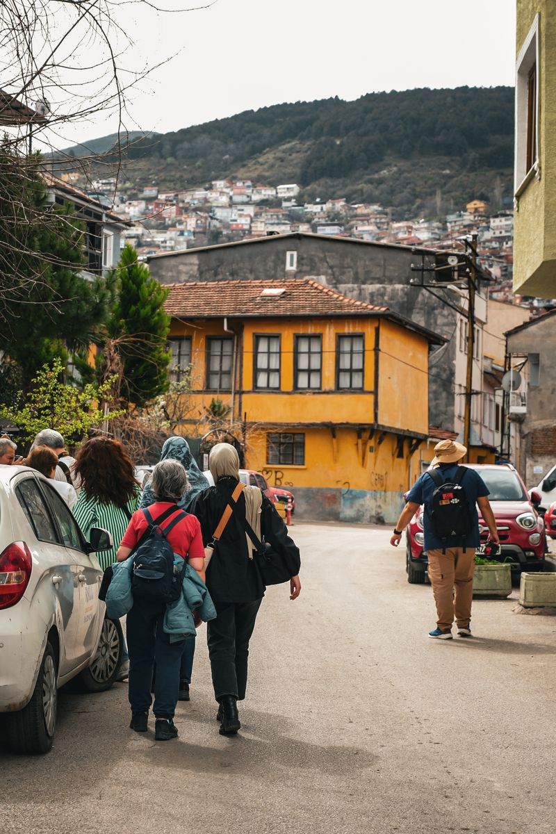 Group of tourists walking through a colorful street with hills in the background, vibrant exploration vibe.
