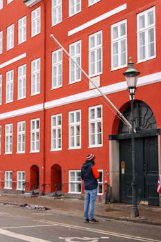 Red building facade in Copenhagen with a lone pedestrian in winter clothing.