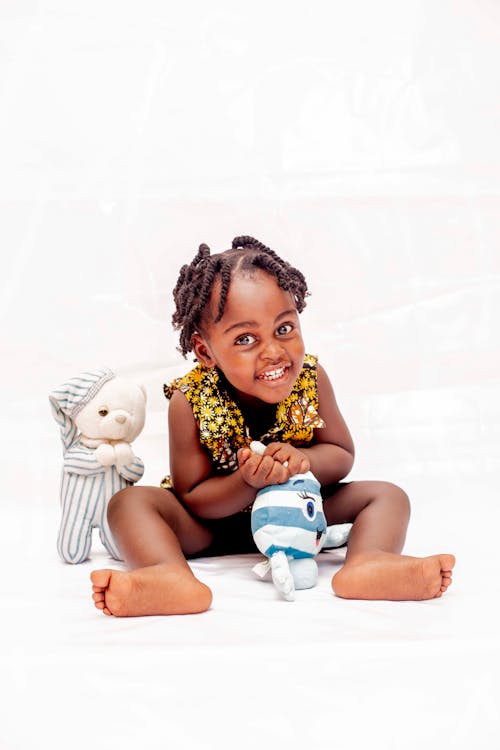 Free Toddler Girl Smiling and Touching Toy Stock Photo