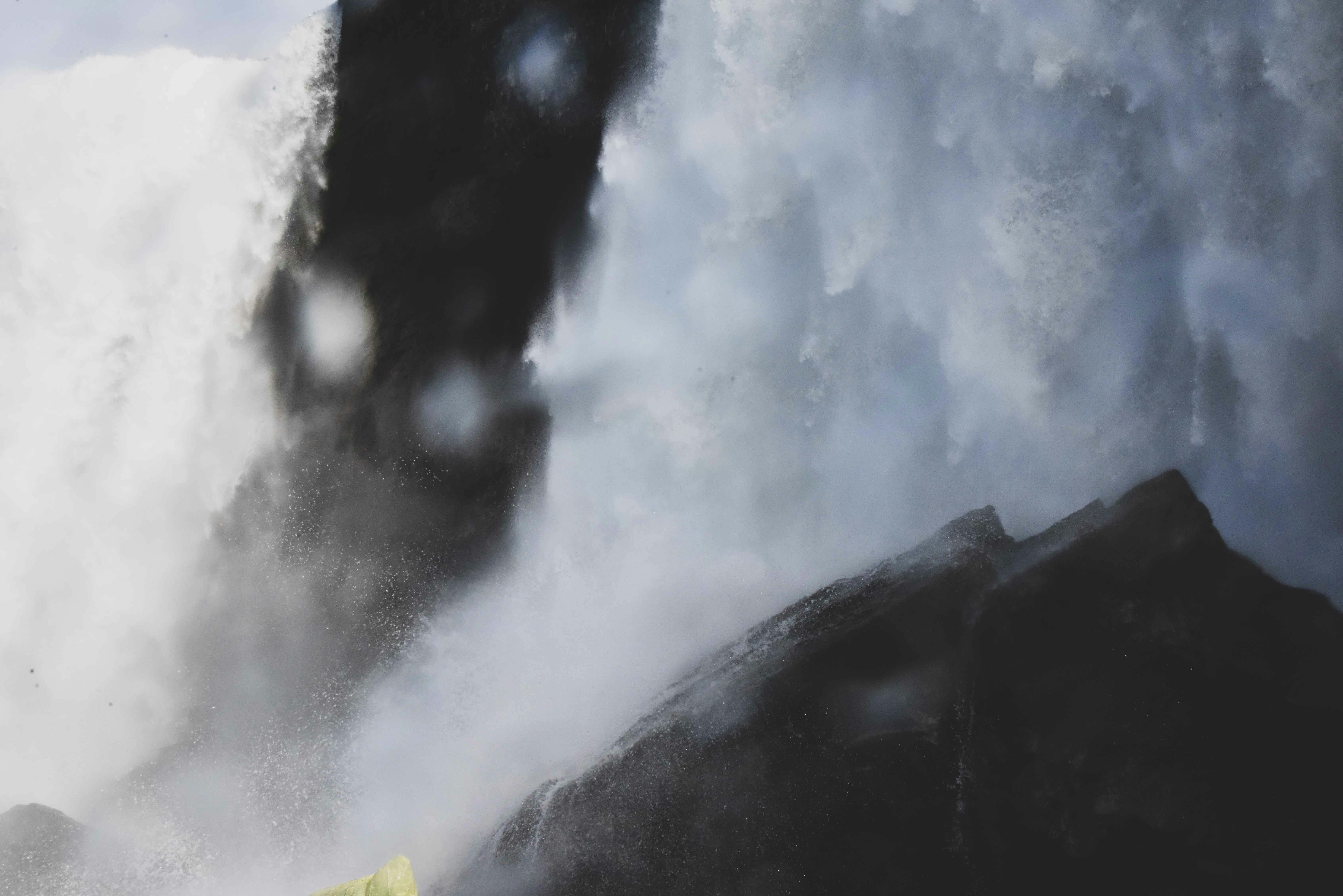 特写镜头中，强大的瀑布从岩石上倾泻而下，笼罩在薄雾与水雾里