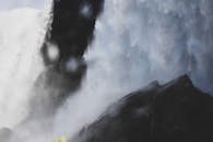 特写镜头中，强大的瀑布从岩石上倾泻而下，笼罩在薄雾与水雾里