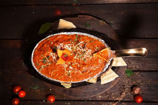 A flavorful Indian curry with vibrant garnish served in a metal dish, perfect for food lovers.