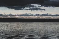 黄昏时分，多云天空充满戏剧性，映衬着宁静的湖景，营造出一种平静的氛围