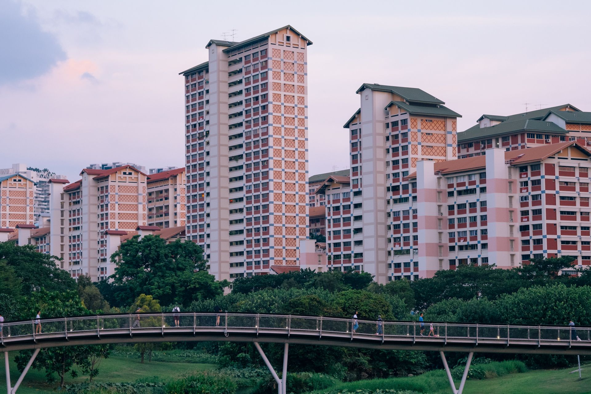 A view of Singapore's high-rise apartments with a pedestrian bridge and greenery.