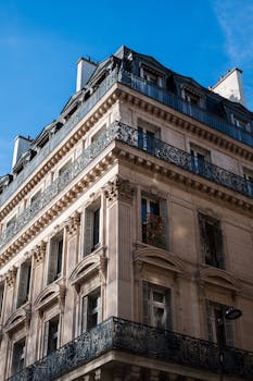 Sunlit corner of a Haussmann-style building with intricate facade details.