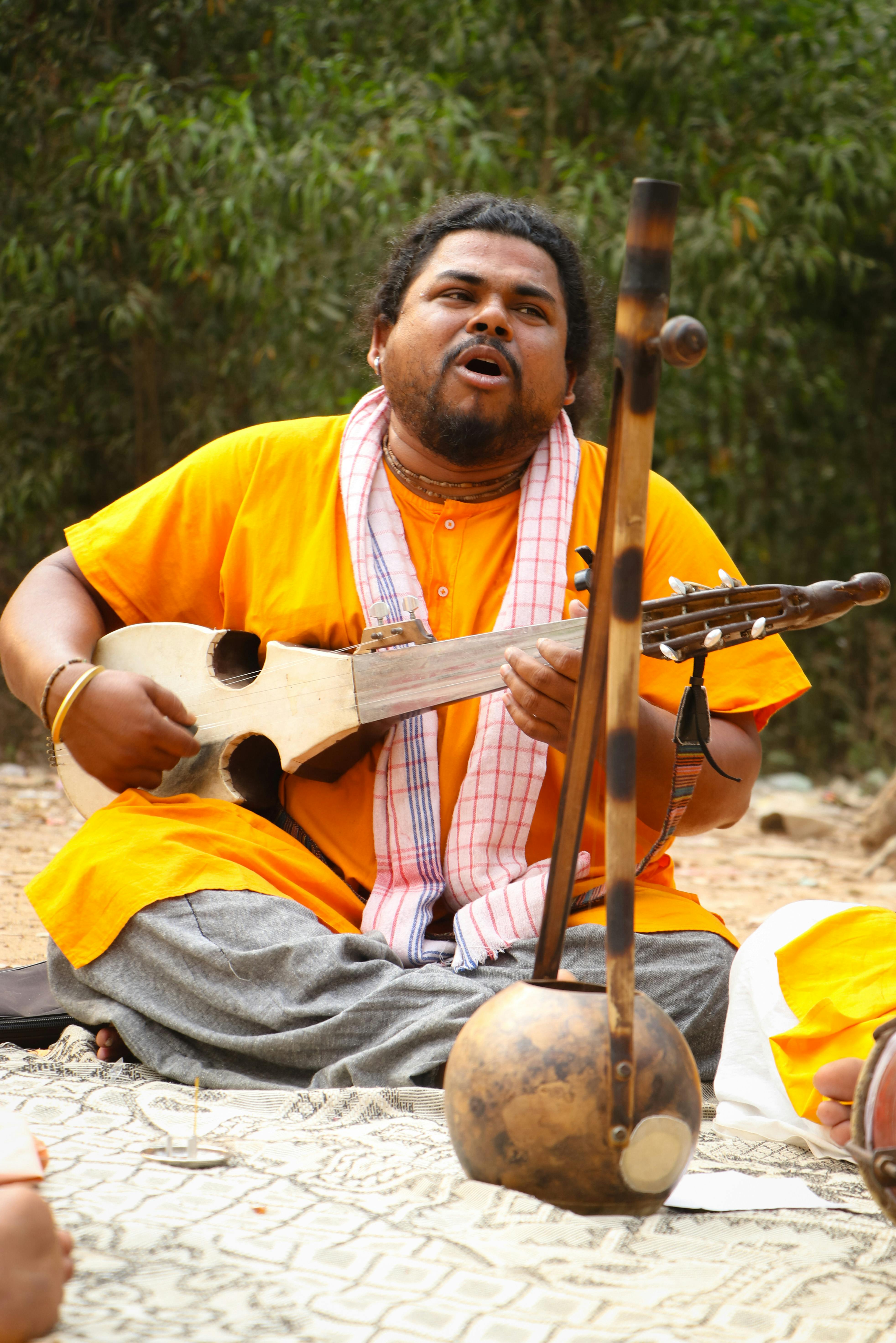A folk musician passionately sings and plays traditional instruments outdoors in Santiniketan.