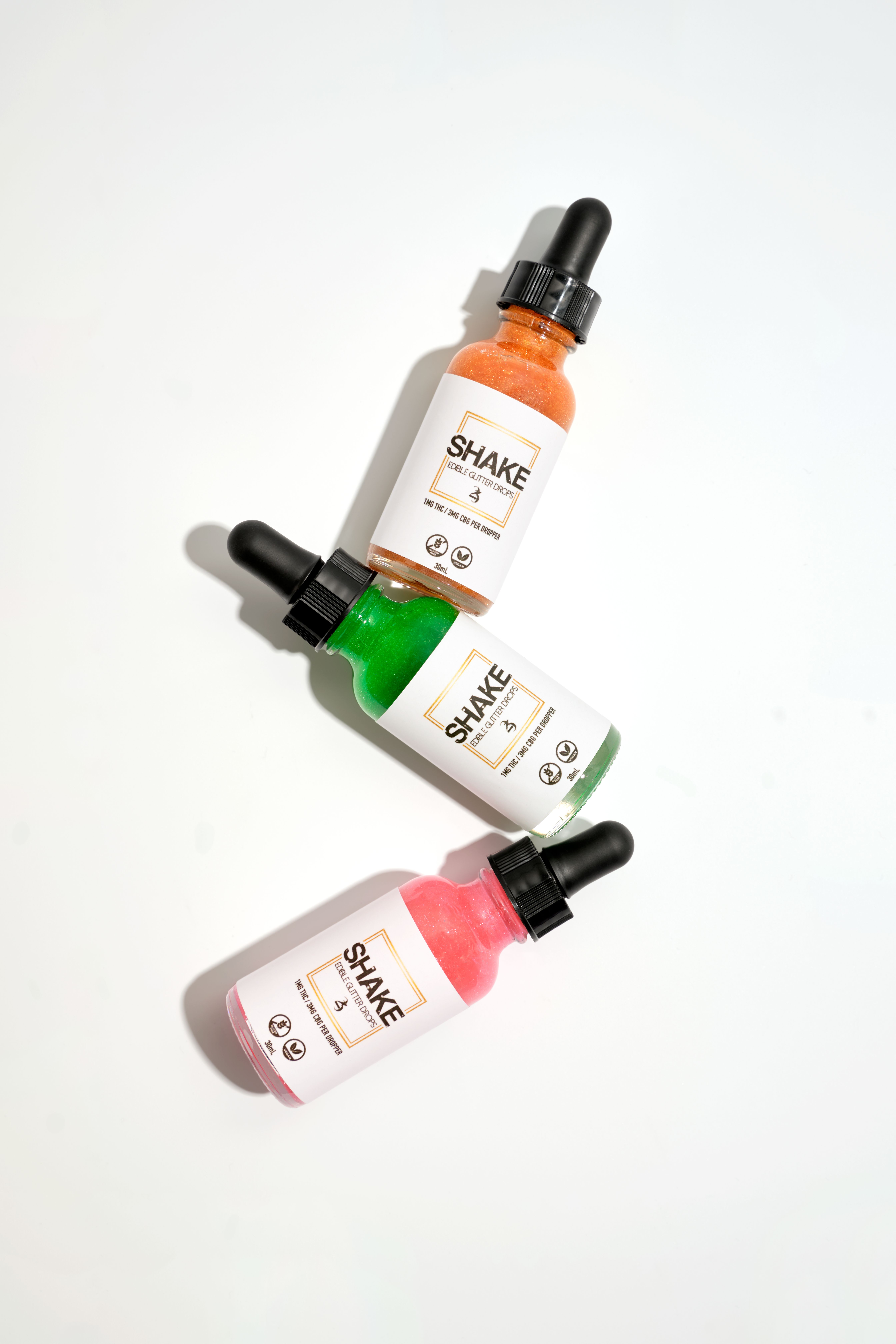 Three vibrant dropper bottles displayed on a white background in flat lay style.