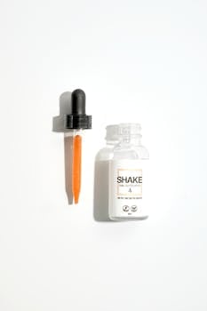Minimalist flat lay of a cosmetic serum bottle with dropper on a white background.