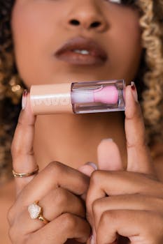 A close-up of a woman displaying a pink beauty product, ideal for cosmetics promotions.
