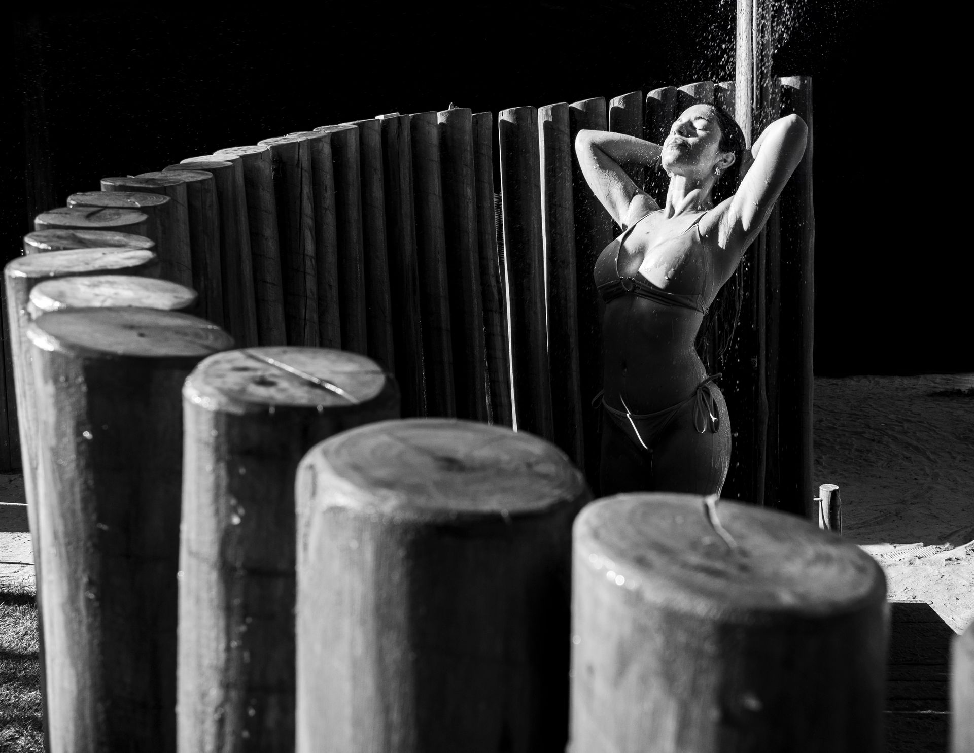 A woman enjoying an outdoor shower on a sunny day at the beach.