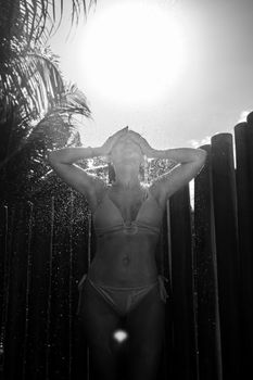 A woman enjoys a refreshing outdoor shower under the sun in Porto Seguro.
