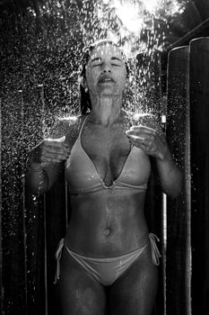 Woman enjoying a refreshing outdoor shower in Porto Seguro, Bahia, Brazil.