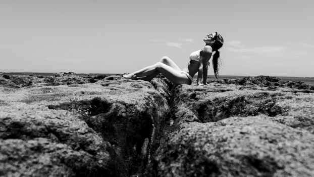 Black and white shot of a woman enjoying the rocky coast in Porto Seguro, Brazil.