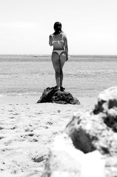Black and white photo of a woman on a beach rock in Porto Seguro, Brazil.