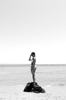 Black and white photo of a person on a rock at Porto Seguro beach.