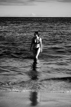 Woman in swimwear walking along a beach in Porto Seguro, Brazil, captured in black and white.