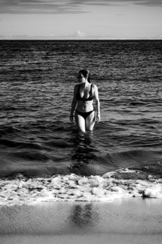 Monochrome image of a woman in a bikini walking in the ocean at Porto Seguro, Brazil.