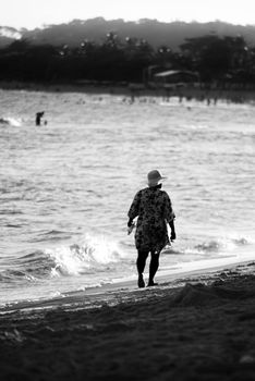 Black and white photo of a woman walking on the beach in Porto Seguro, Brazil.
