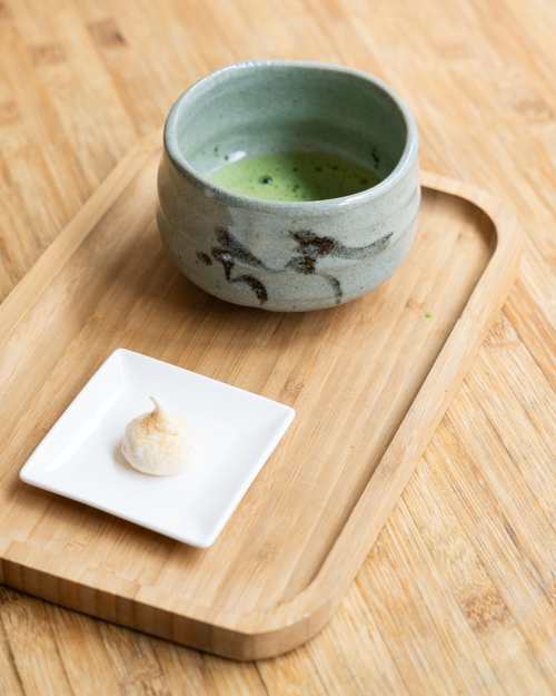 Free Ceramic cup of matcha green tea with dessert on a wooden tray, minimalistic setting. Stock Photo