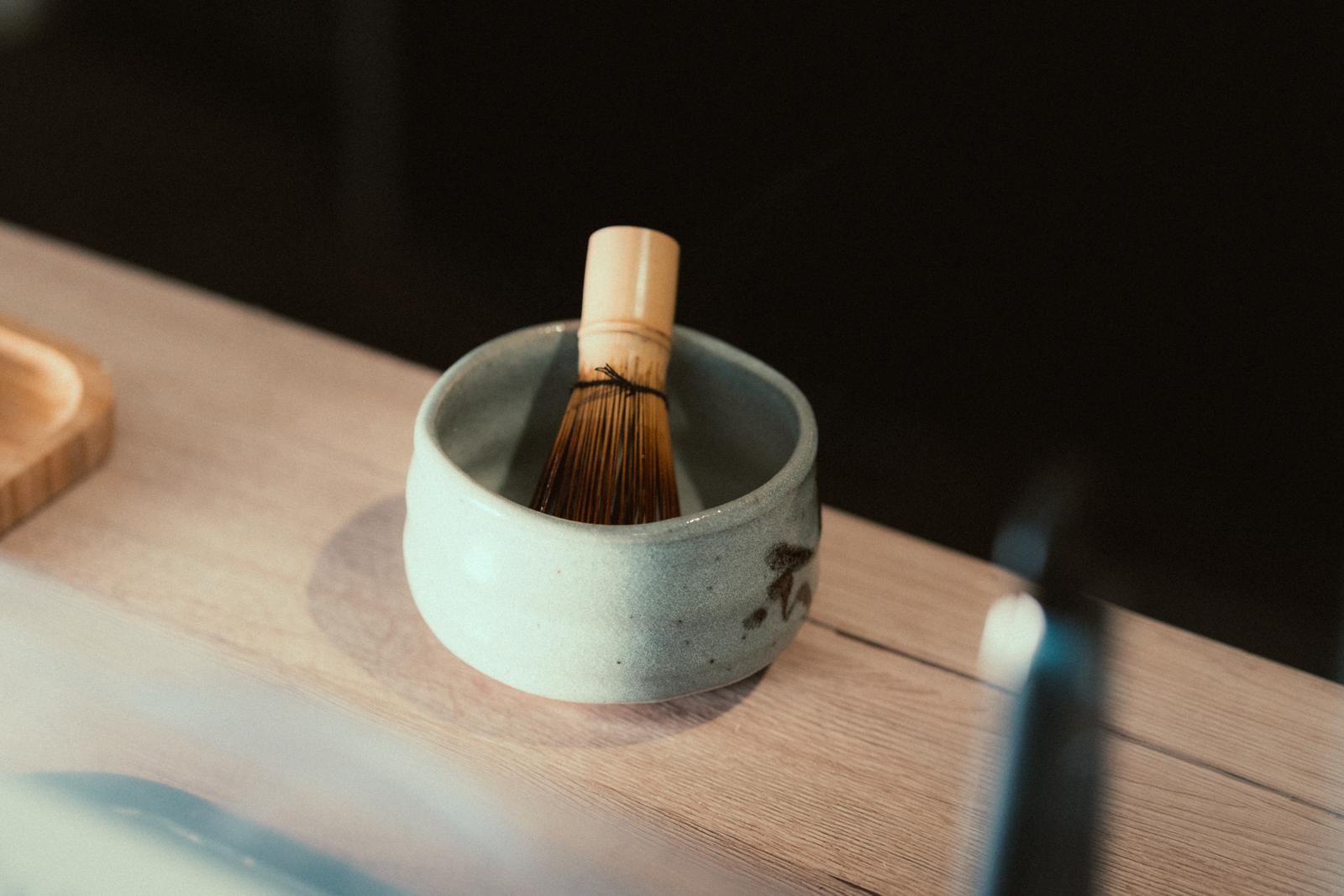 Bamboo matcha whisk resting inside a rounded ceramic bowl on a wooden table