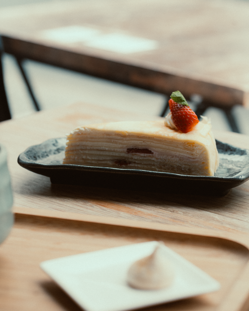 Free A slice of tasty mille crepe cake topped with a fresh strawberry on a dark plate. Stock Photo