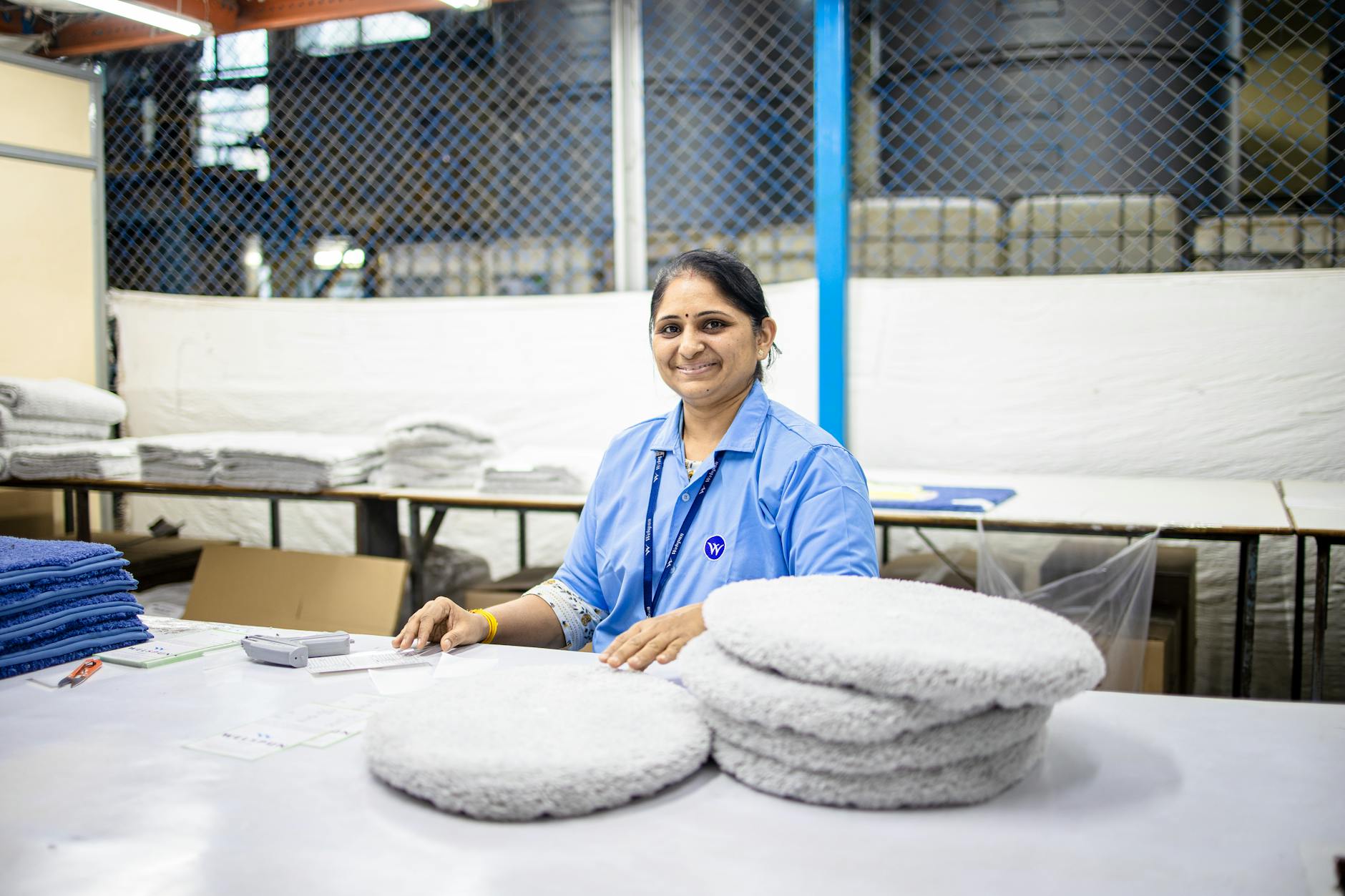 A smiling female textile worker sorting fabrics in a factory setting.