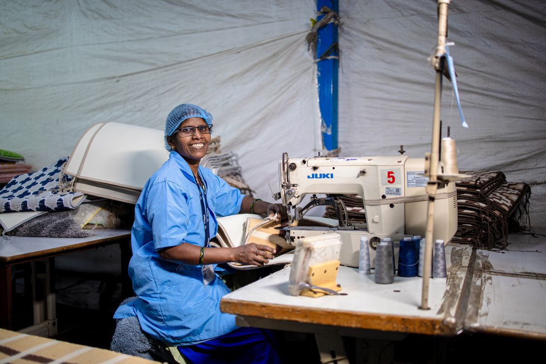 Smiling Textile Worker Sewing in Factory Environment · Free Stock Photo