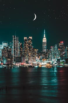 迷人的纽约市天际线在夜间展现，摩天大楼与月亮一同被照亮