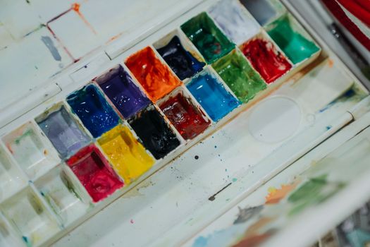 A vibrant and colorful palette of watercolor paints arranged in a neat grid.