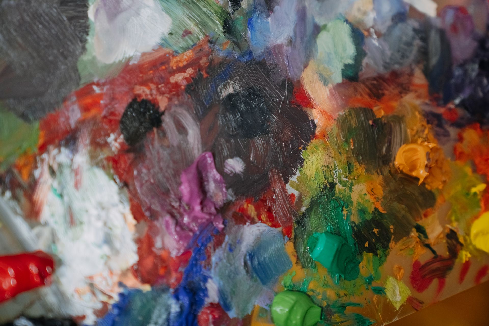 Close-up of a colorful abstract oil painting on a palette, showcasing vibrant hues.
