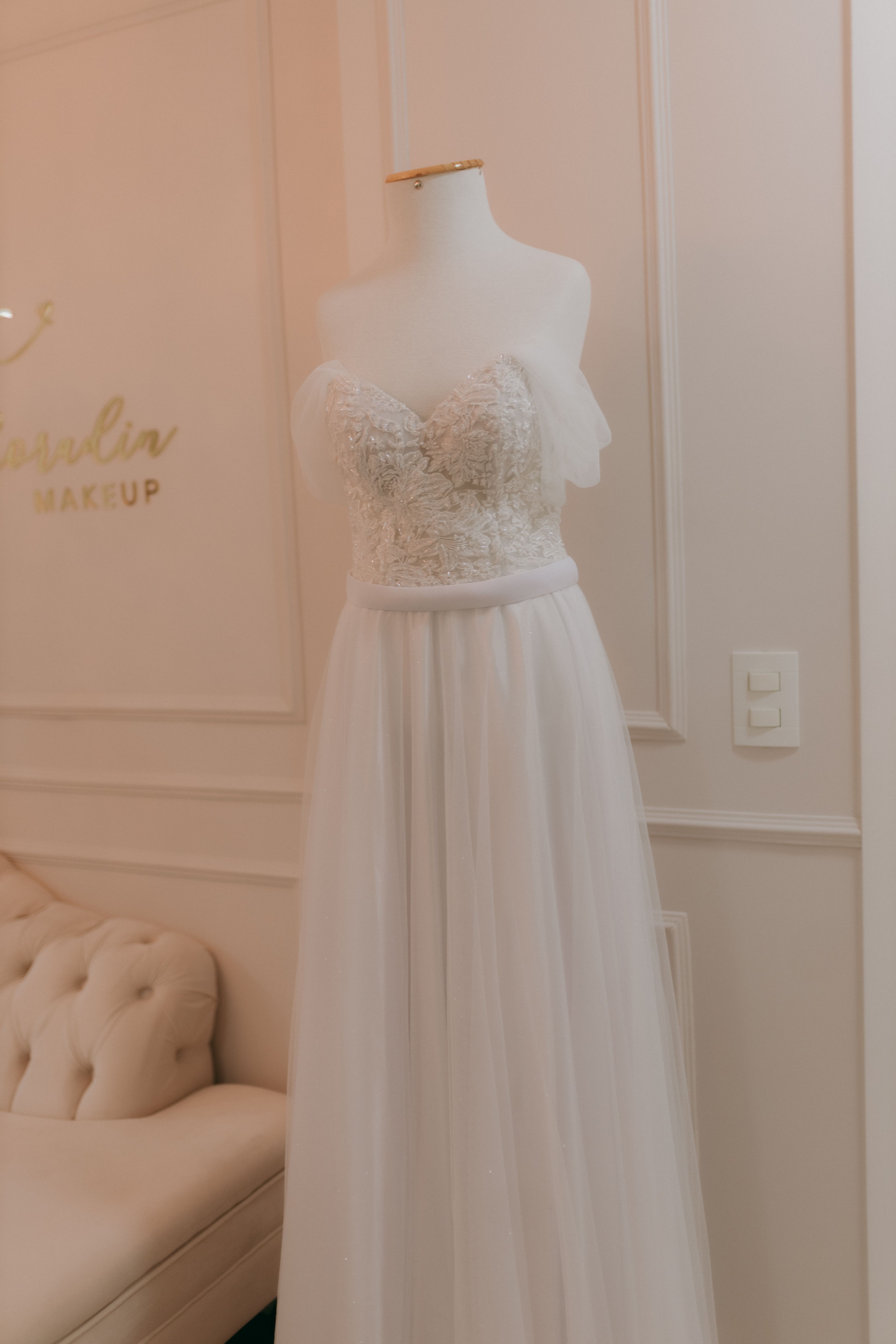 Stylish white wedding gown displayed on mannequin in elegant showroom.