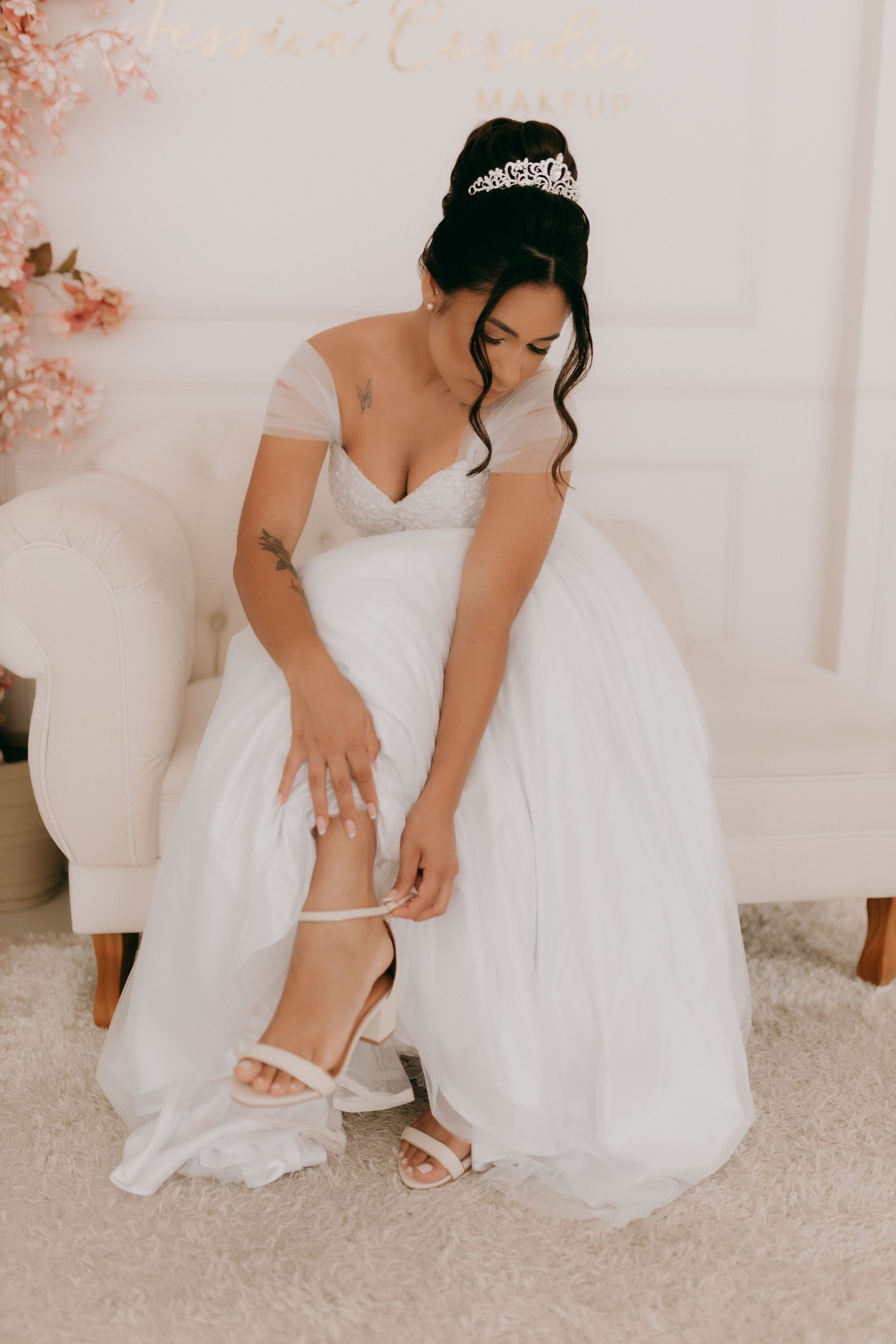 Bride in white gown adjusting garter belt in elegant room setting.