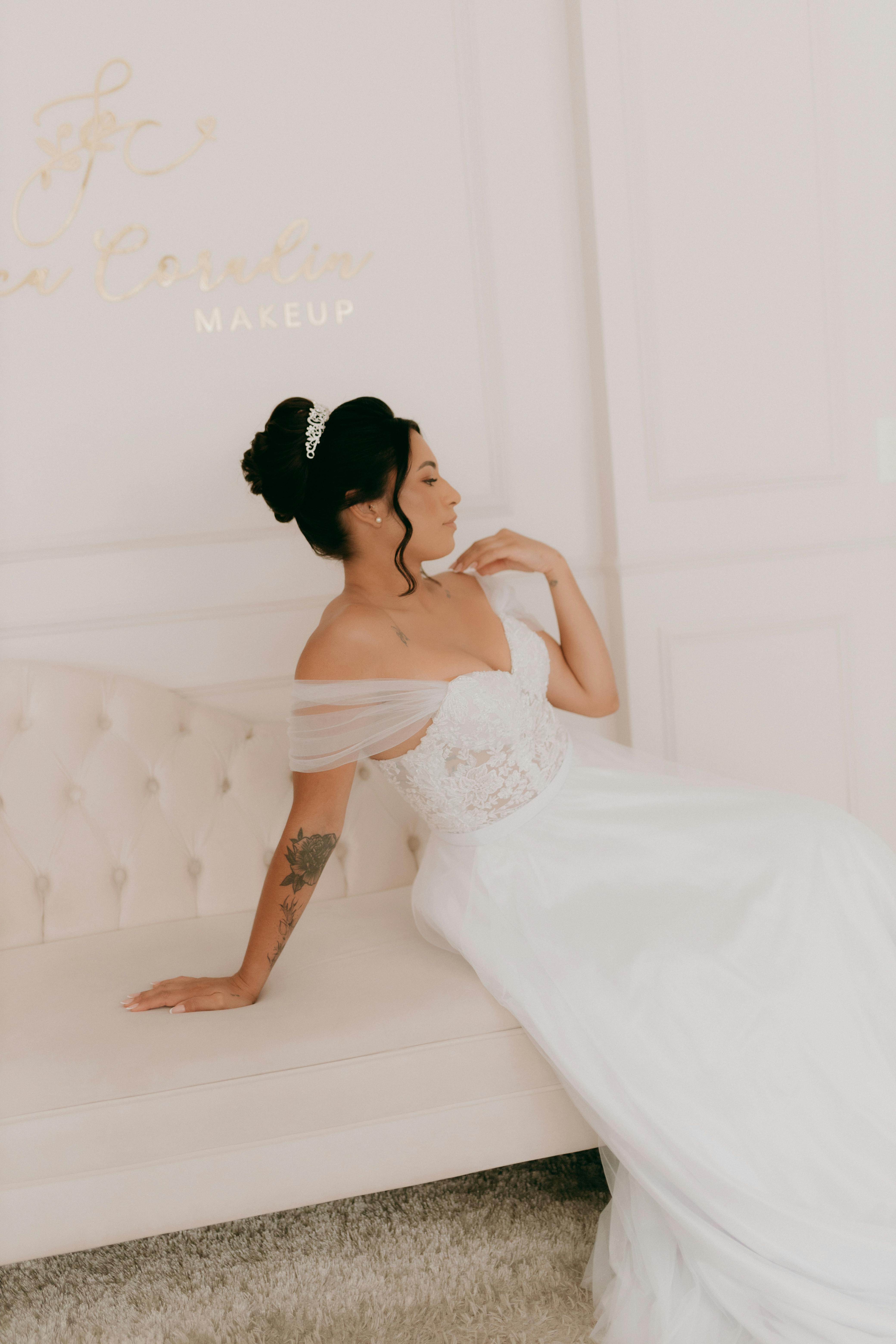A bride in a stylish satin gown sitting indoors, exuding grace and elegance.