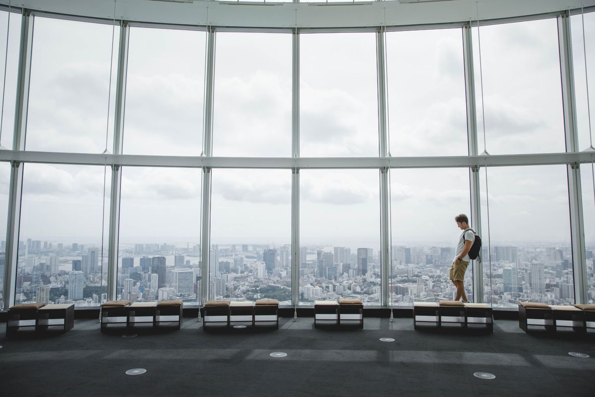 Visitor looking out over the Tokyo skyline from a high-rise observation deck window