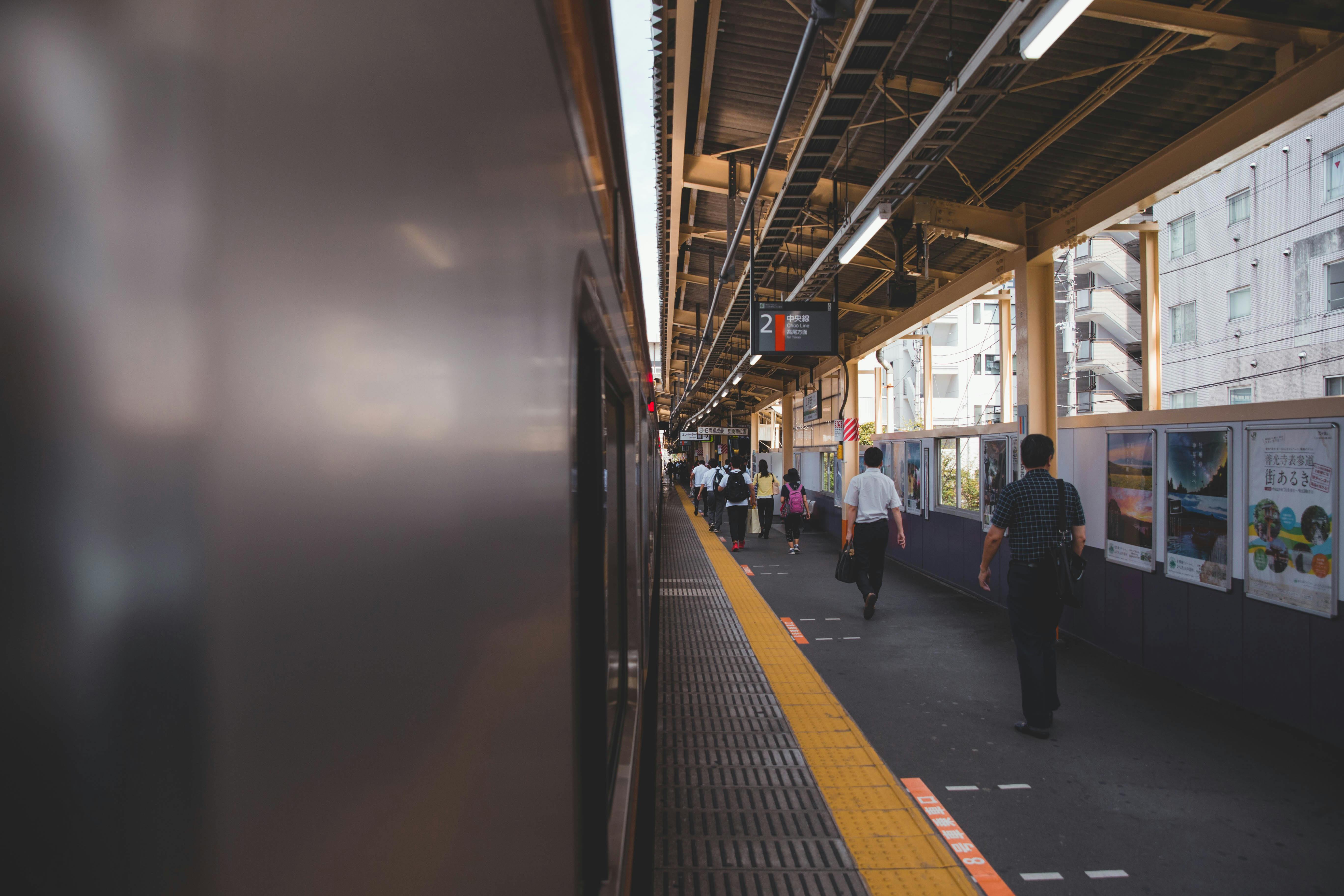 A bustling train platform in Japan with business people during the day.