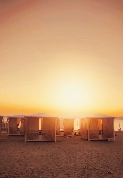 Free Peaceful beach scene with cabanas at sunset, offering a warm and tranquil atmosphere. Stock Photo