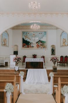 A beautifully decorated church altar ready for a wedding ceremony, featuring floral arrangements.
