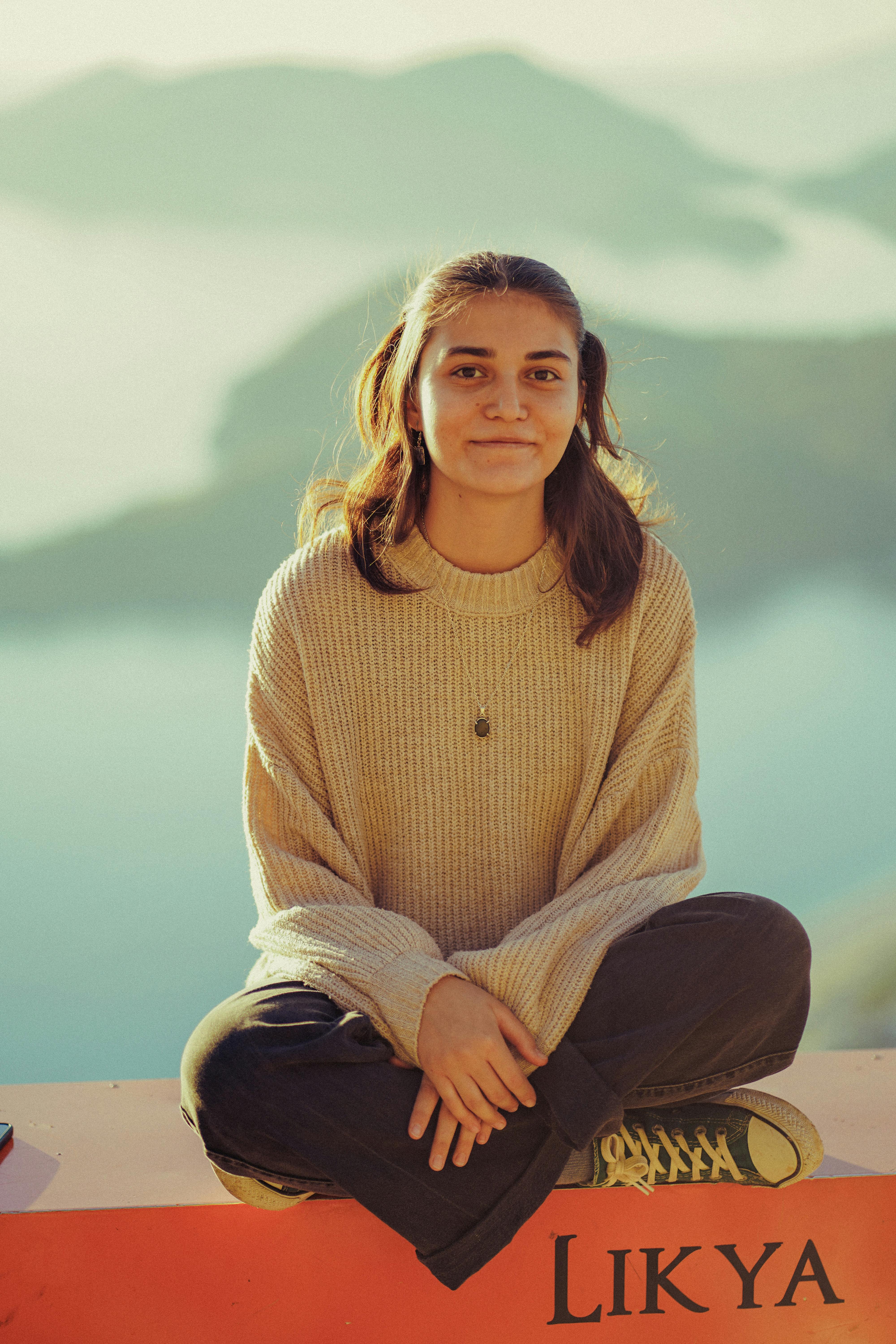 Young woman enjoying a serene view, sitting comfortably outdoors. Perfect for lifestyle and travel imagery.