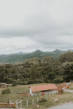 Tranquil rural scene with a red roofed barn and lush green mountains in the background.