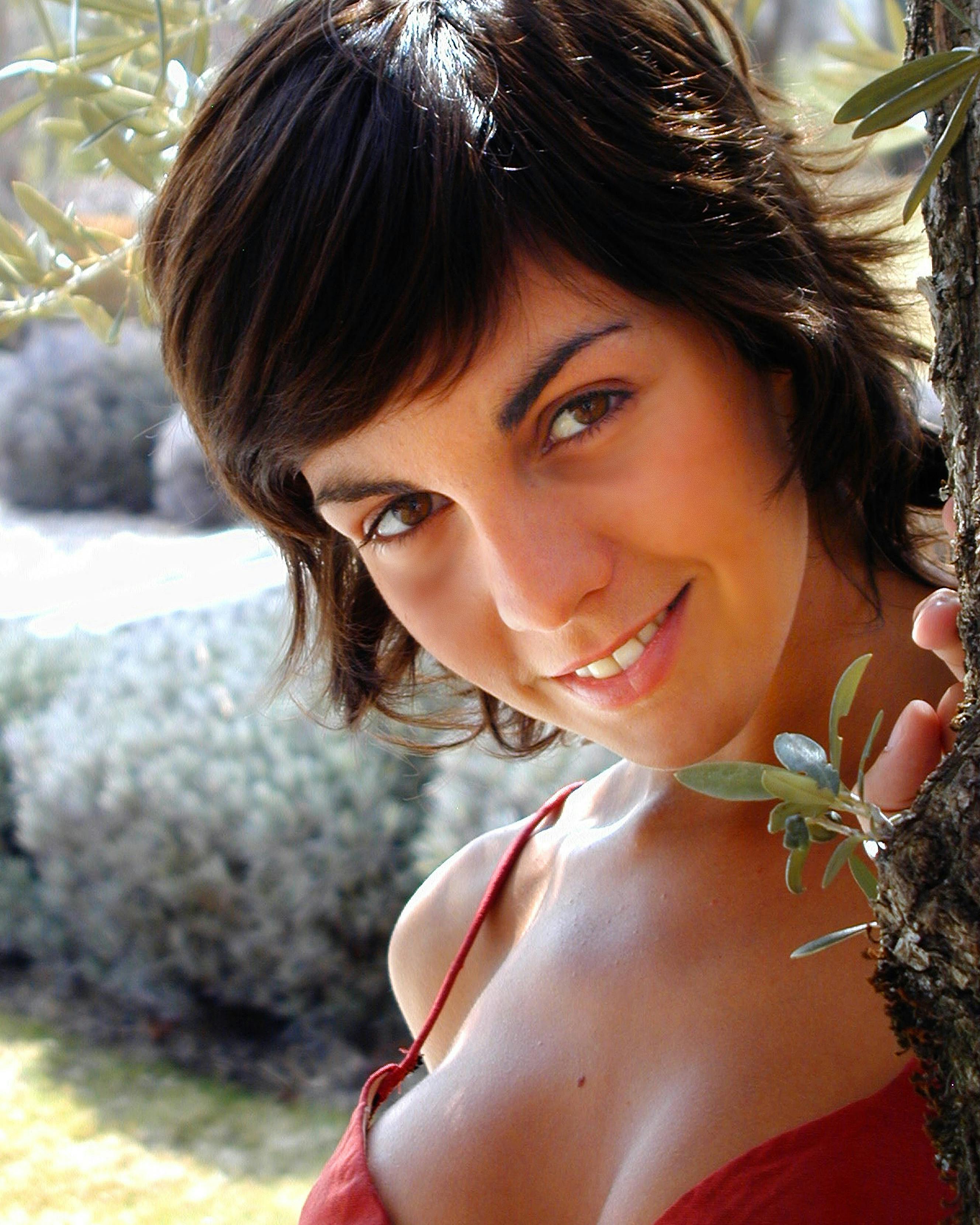 Portrait of a smiling woman enjoying a sunny day outdoors surrounded by nature.