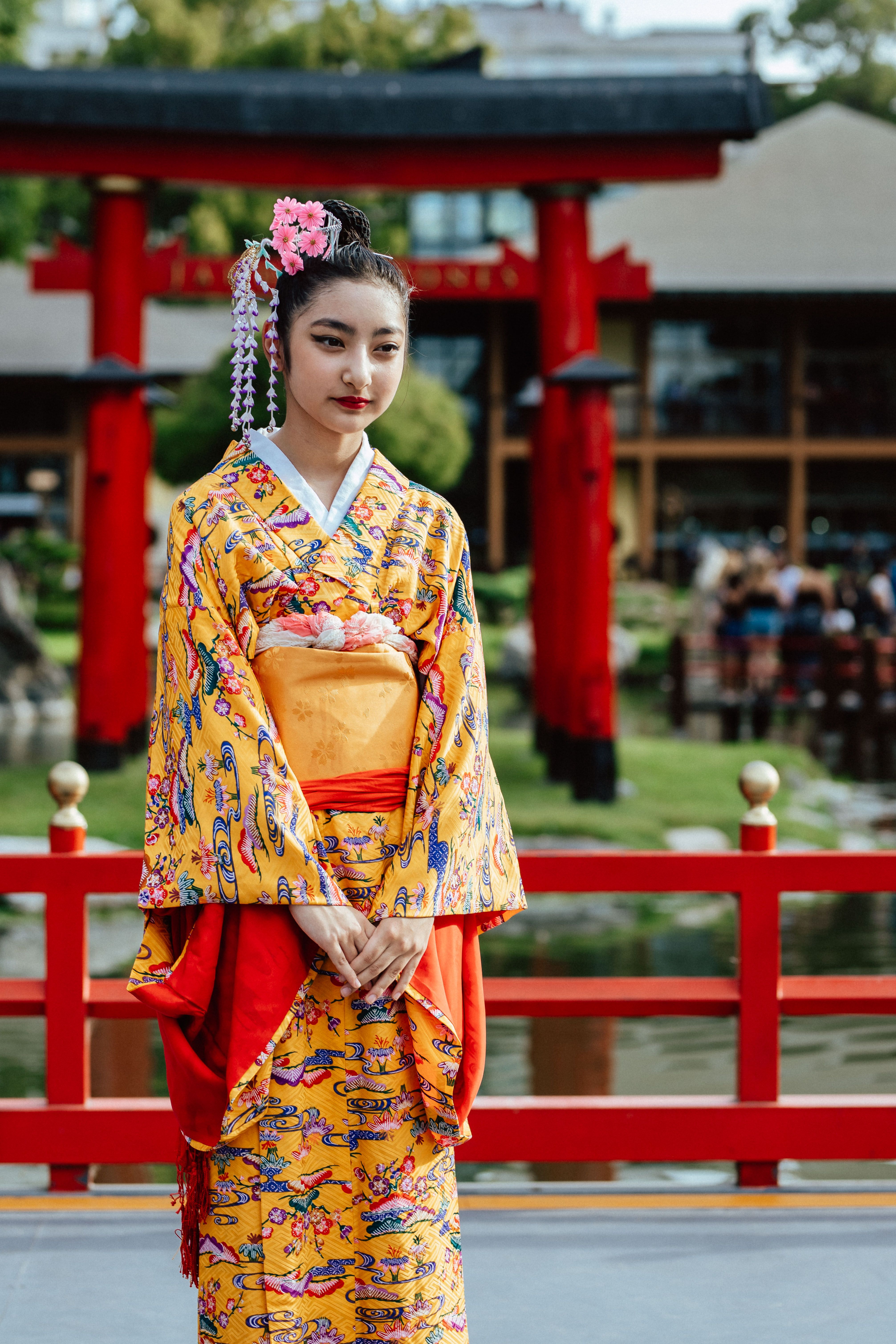 A young woman in a vibrant kimono poses in a Japanese garden in Buenos Aires.