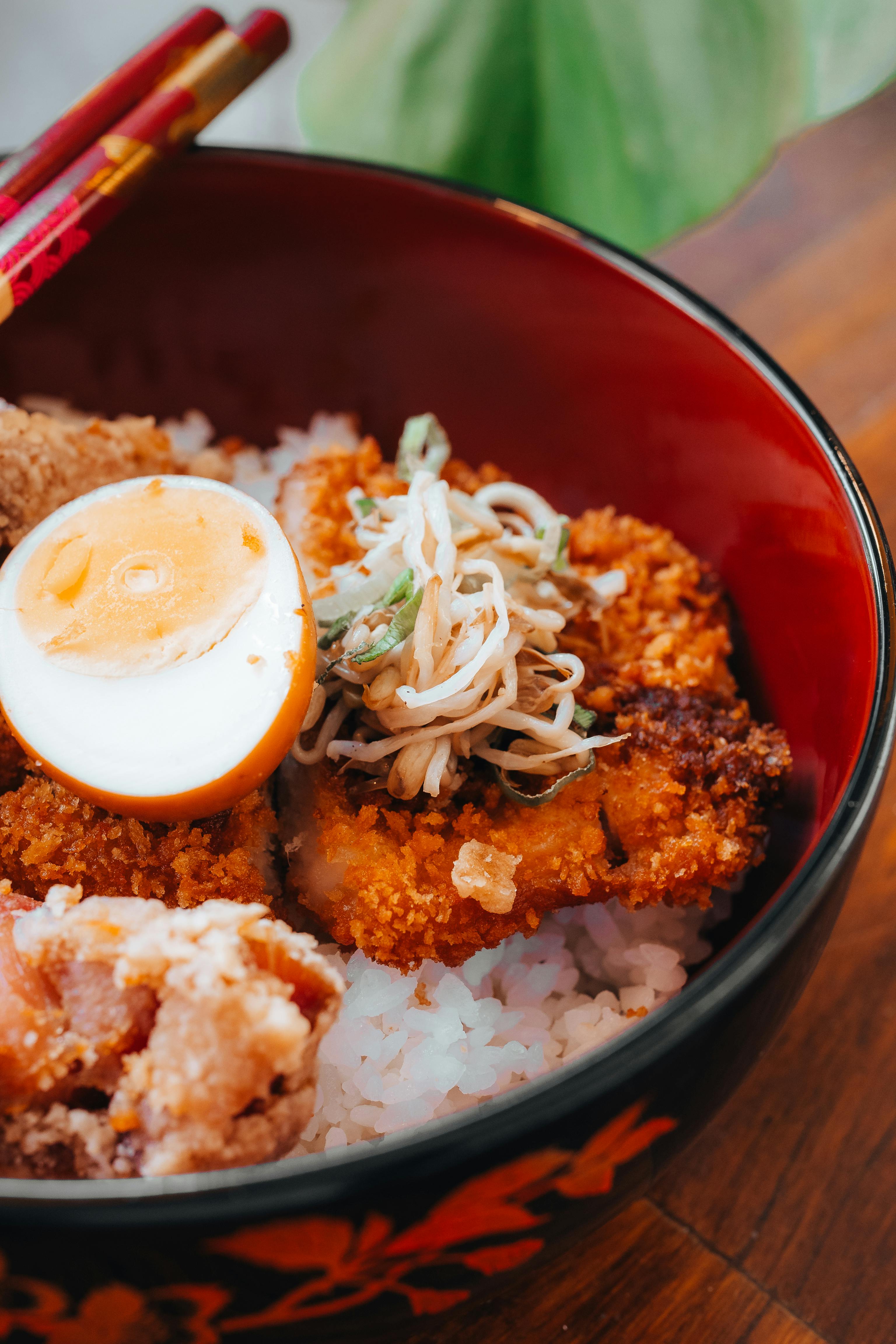 A savory Japanese rice bowl topped with katsu, boiled egg, and vegetables.
