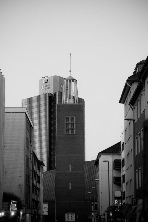 Free Urban cityscape featuring a central tower and surrounding buildings in black and white. Stock Photo