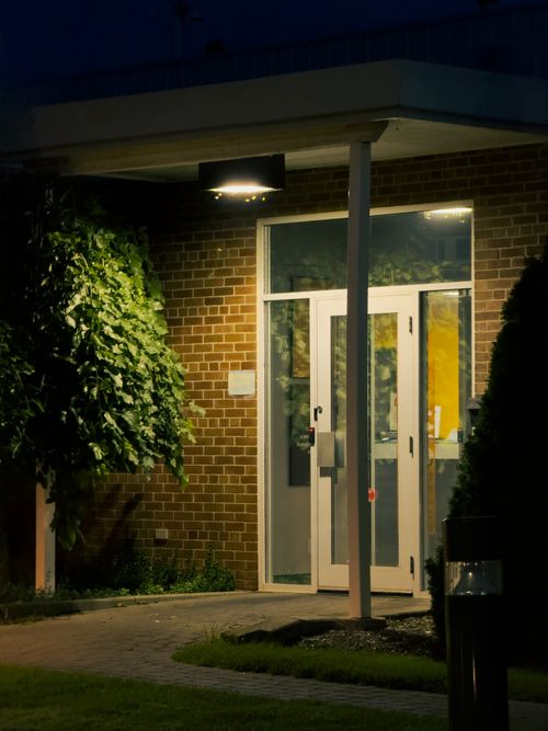 Free A night view of a lit building entrance with greenery. Stock Photo