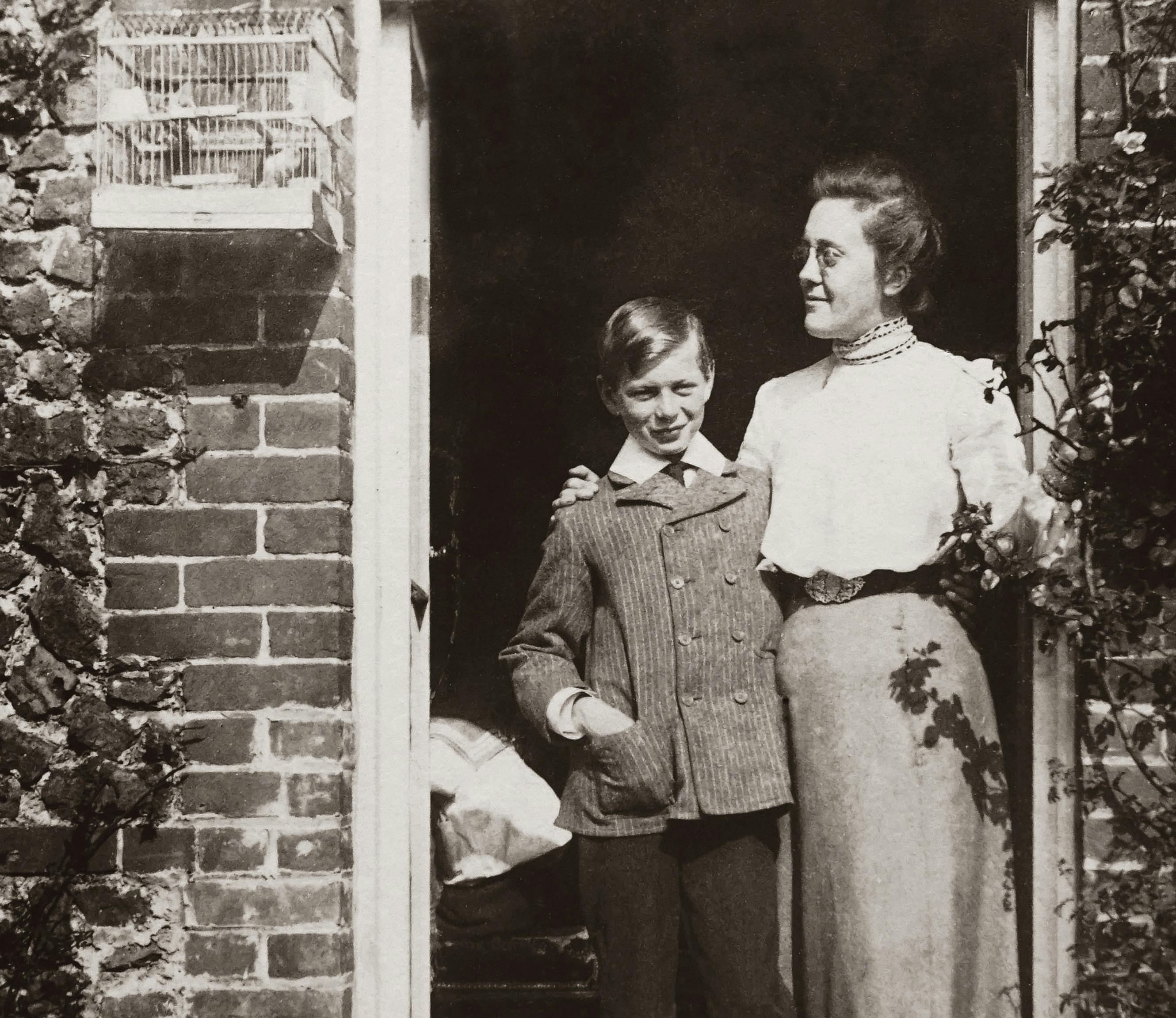 black and white photo of mother and son standing by the doorway