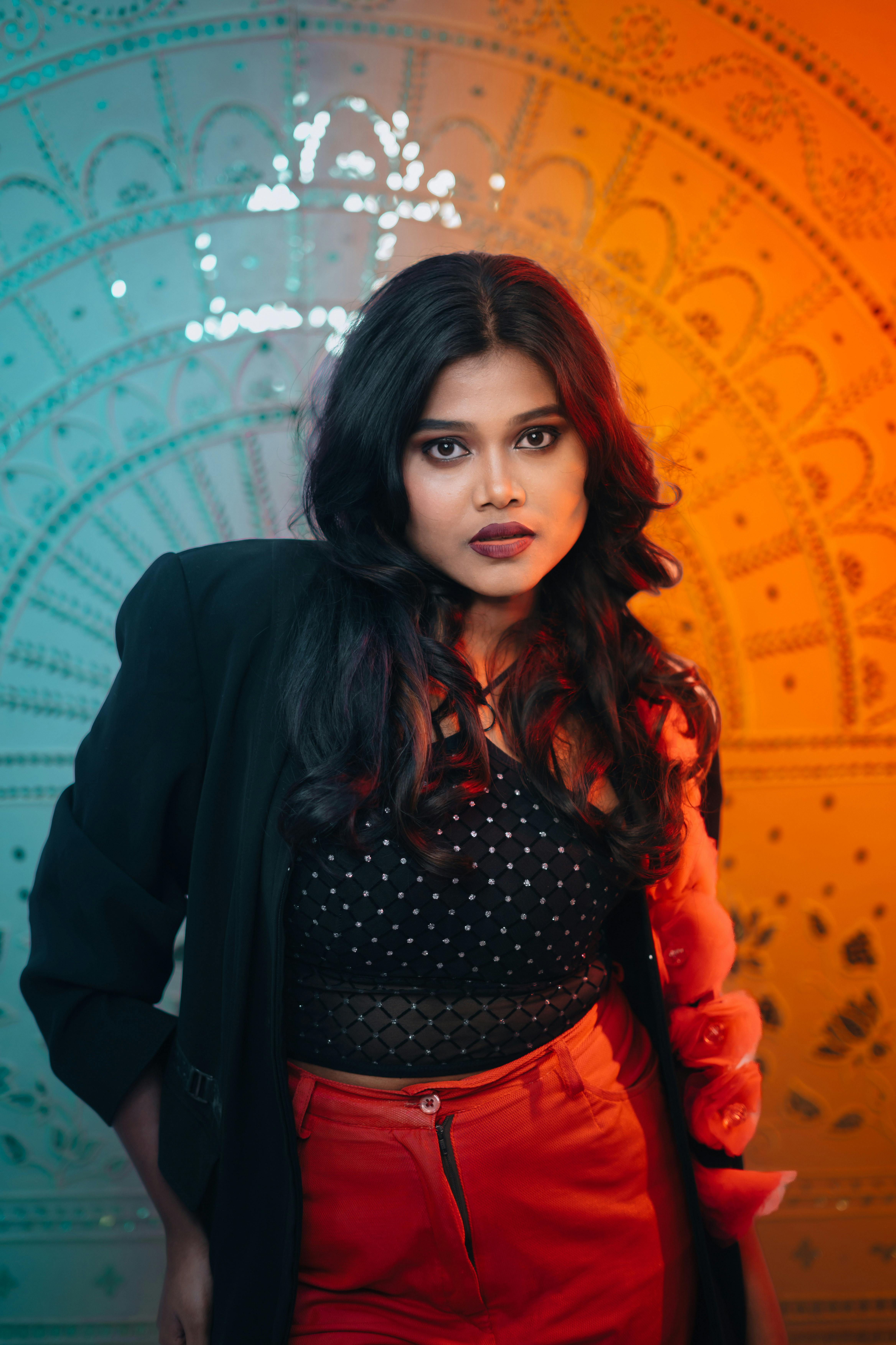 Gratis Wanita modis berpose dengan latar belakang warna-warni, memancarkan kepercayaan diri dan gaya. Foto Stok